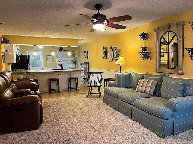 carpeted living room featuring ceiling fan, sink, and a textured ceiling