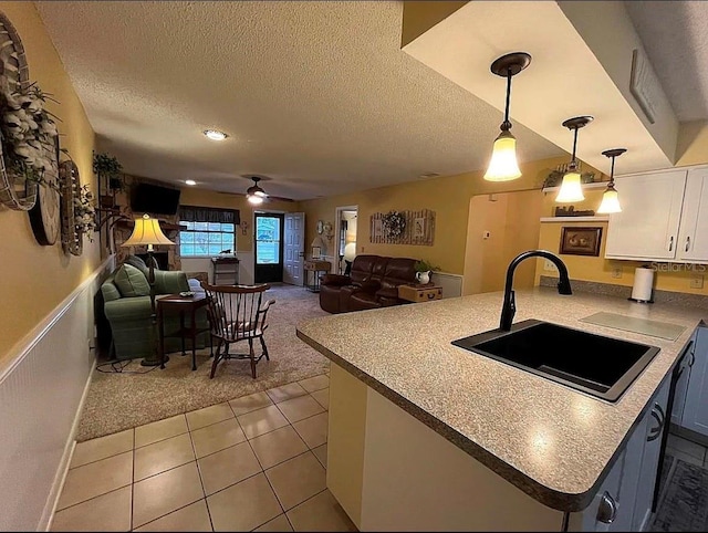 kitchen with pendant lighting, sink, ceiling fan, white cabinetry, and light colored carpet