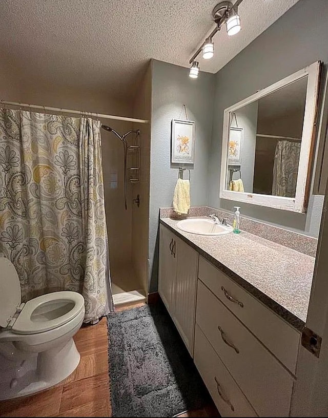 bathroom with hardwood / wood-style flooring, a shower with shower curtain, vanity, a textured ceiling, and toilet