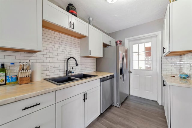 kitchen with sink, appliances with stainless steel finishes, tasteful backsplash, and white cabinetry