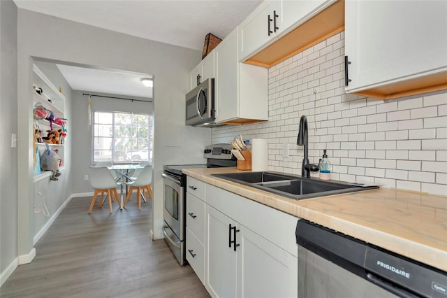 kitchen with white cabinets, appliances with stainless steel finishes, backsplash, and sink