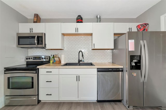 kitchen featuring stainless steel appliances, white cabinetry, sink, and backsplash