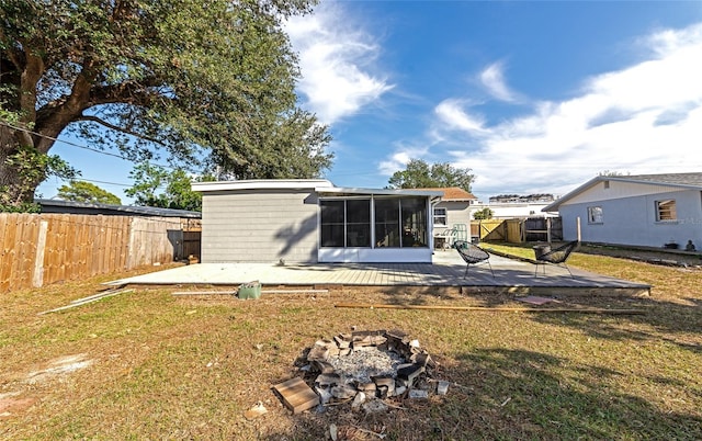 back of property with an outdoor fire pit, a yard, a sunroom, and a wooden deck