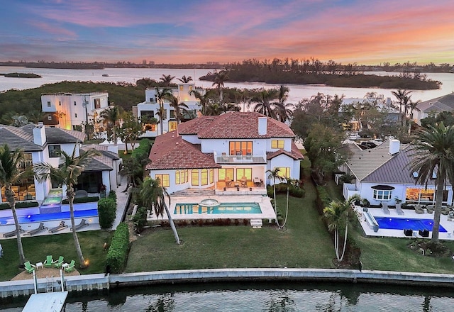 aerial view at dusk featuring a water view