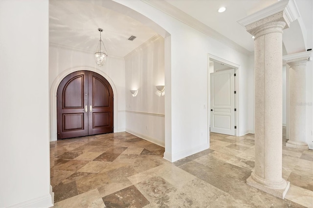 foyer with an inviting chandelier, crown molding, and ornate columns