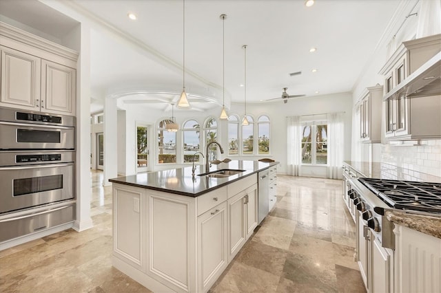 kitchen featuring sink, pendant lighting, stainless steel appliances, cream cabinets, and backsplash