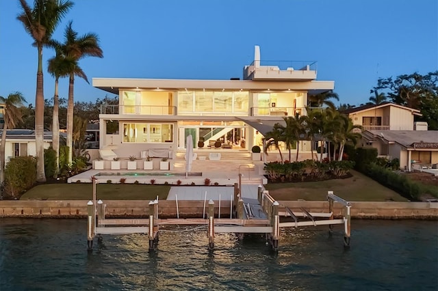 back of property featuring a swimming pool, a patio, a balcony, and a water view