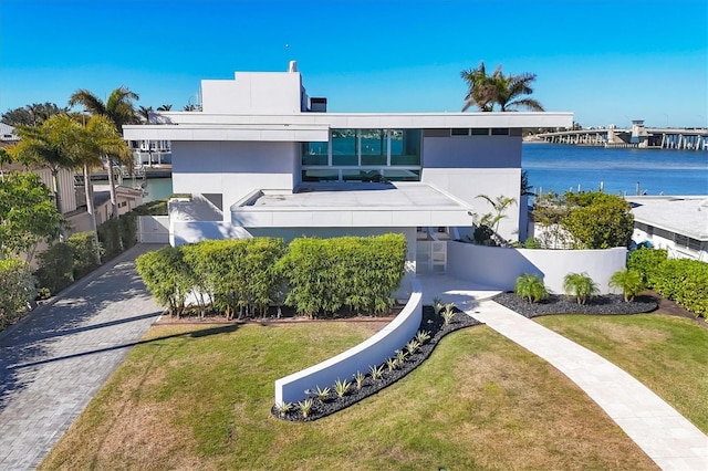 contemporary house featuring a water view and a front lawn