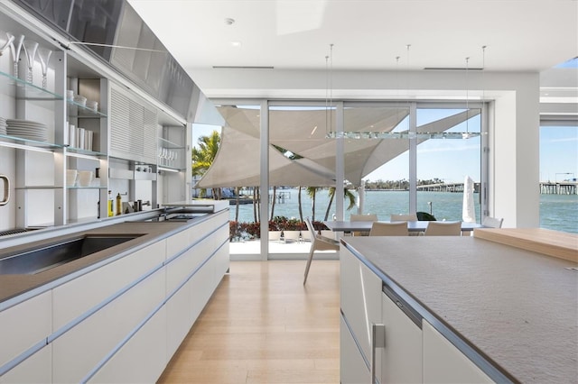 kitchen featuring white cabinetry, a water view, and light wood-type flooring