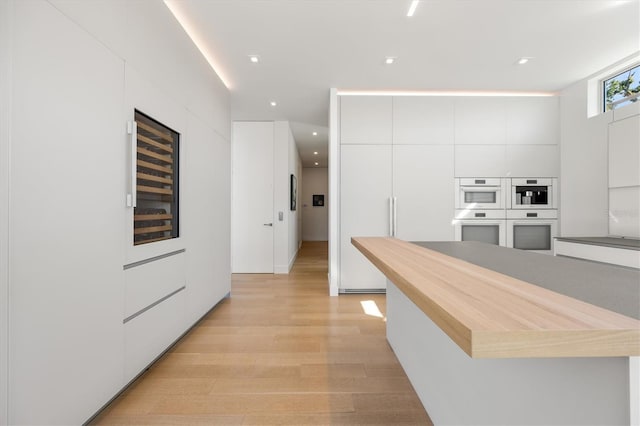 kitchen featuring white cabinets, double oven, and light hardwood / wood-style flooring