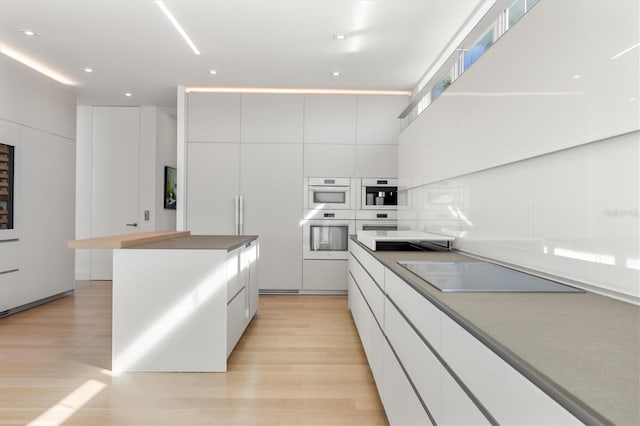 kitchen featuring white cabinetry, light wood-type flooring, black electric stovetop, and double oven