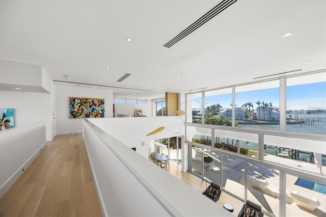 hall featuring light hardwood / wood-style floors, expansive windows, and a water view