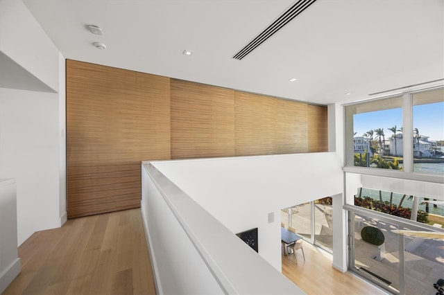 hallway featuring floor to ceiling windows, a water view, and light hardwood / wood-style floors