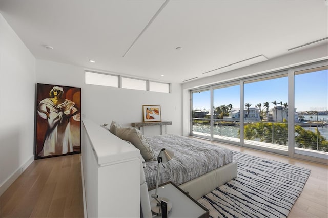 bedroom featuring a water view and hardwood / wood-style flooring