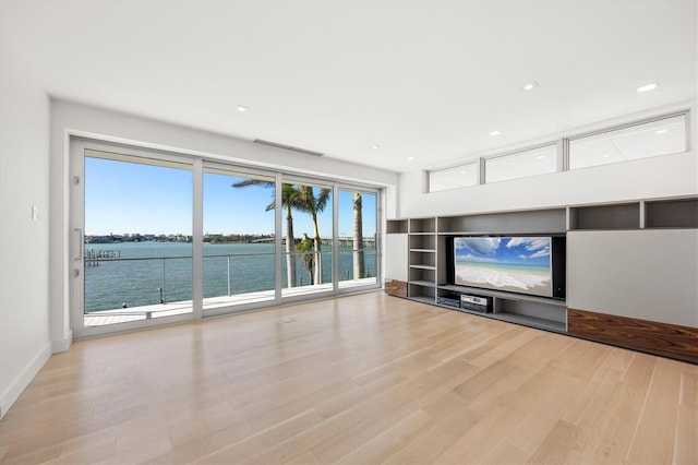 unfurnished living room featuring a water view and light hardwood / wood-style flooring