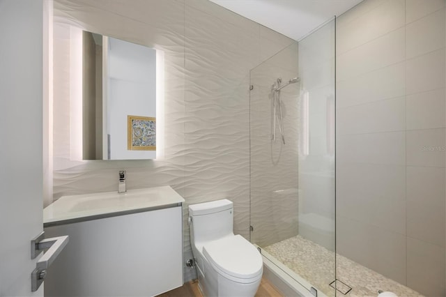 bathroom featuring tile walls, vanity, toilet, and a tile shower