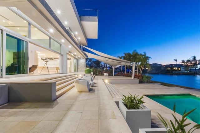 pool at dusk featuring a patio and a water view