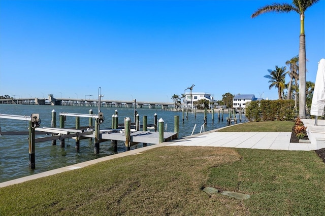 view of dock with a yard and a water view