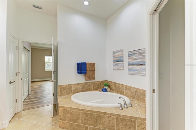 bathroom featuring a relaxing tiled tub and tile patterned flooring