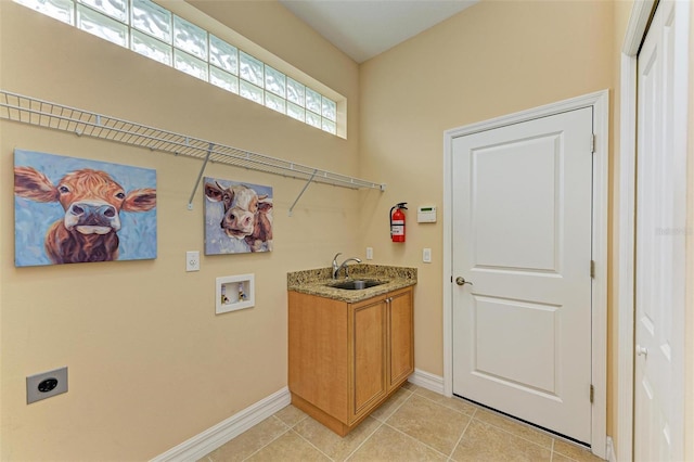 laundry area with electric dryer hookup, sink, washer hookup, and light tile patterned floors