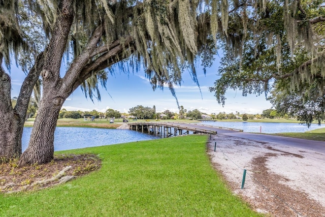 view of dock with a water view and a lawn