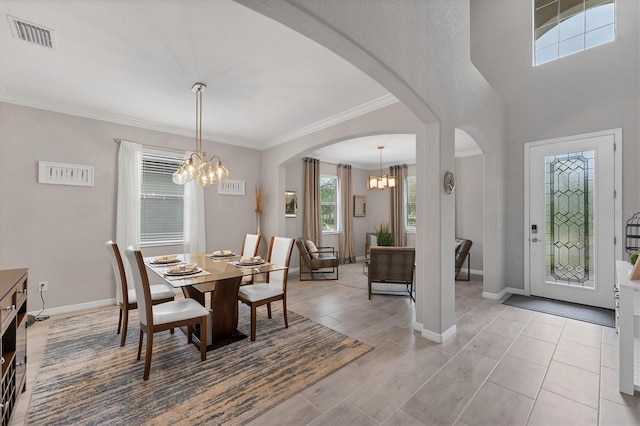 tiled dining area featuring crown molding and a chandelier