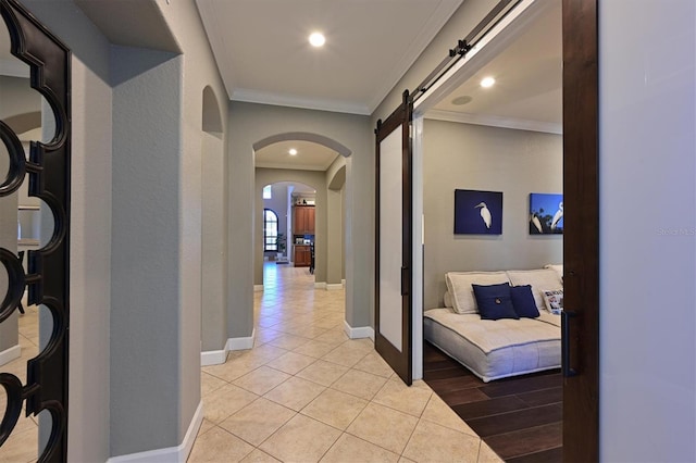 hallway featuring light tile patterned floors, a barn door, and ornamental molding