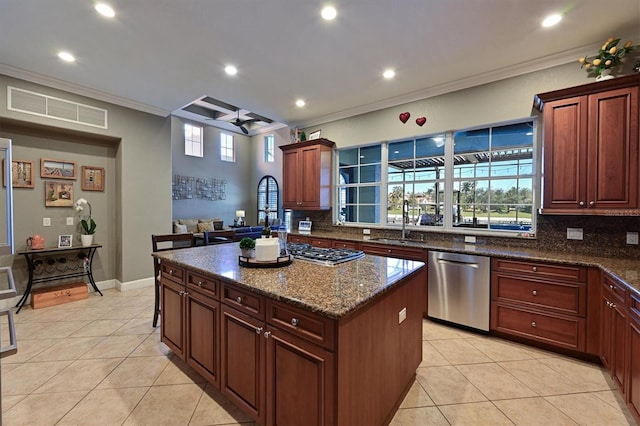 kitchen featuring sink, dark stone countertops, light tile patterned floors, appliances with stainless steel finishes, and a kitchen island