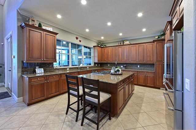 kitchen featuring sink, a center island, dark stone counters, a breakfast bar, and ornamental molding