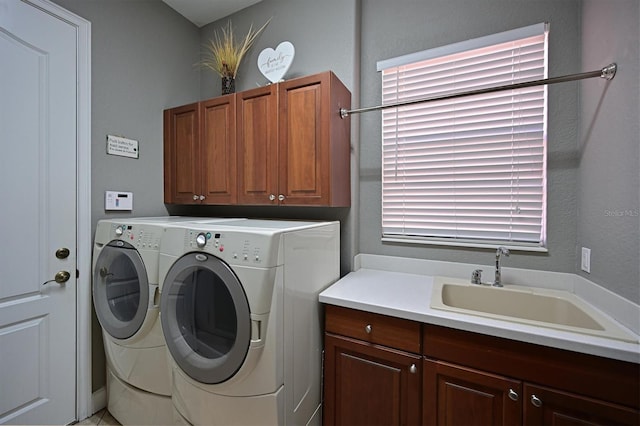 clothes washing area with separate washer and dryer, sink, and cabinets