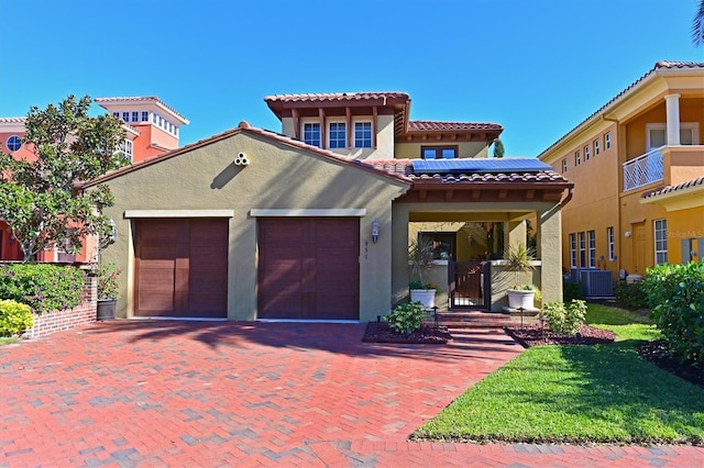 mediterranean / spanish-style house with solar panels, central AC, and a garage