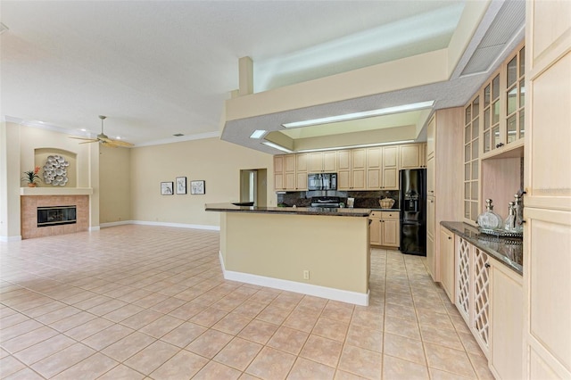 kitchen with a tiled fireplace, light tile patterned flooring, dark stone countertops, and black appliances