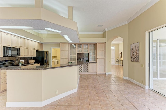 kitchen featuring light tile patterned flooring, dark stone countertops, ornamental molding, decorative backsplash, and black appliances