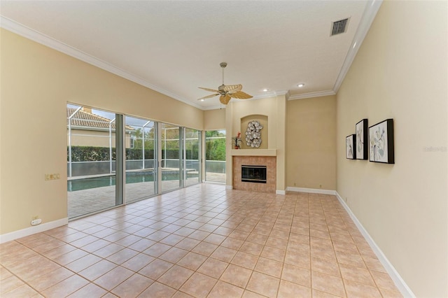 unfurnished living room with light tile patterned floors, ornamental molding, a tile fireplace, and ceiling fan