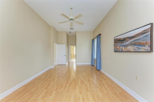 unfurnished room with ceiling fan, a textured ceiling, and light wood-type flooring