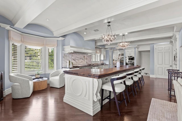 kitchen with decorative light fixtures, white cabinetry, a large island, wall chimney exhaust hood, and wood counters