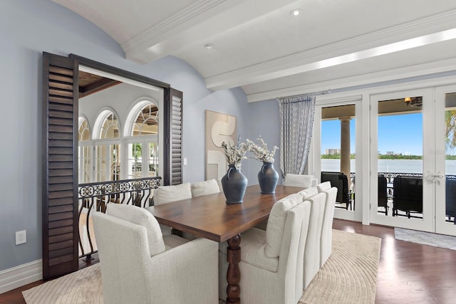 dining room featuring dark hardwood / wood-style floors, lofted ceiling, a water view, and a healthy amount of sunlight