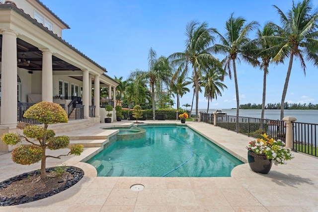 view of swimming pool featuring a water view, ceiling fan, a patio, and an in ground hot tub