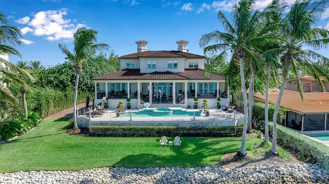 back of property with a swimming pool with hot tub, a yard, and a patio