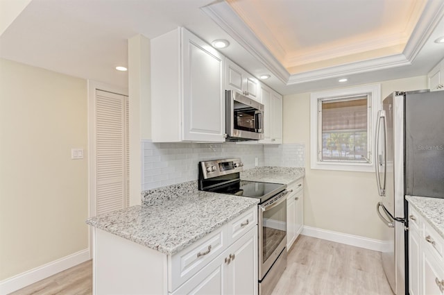 kitchen featuring backsplash, a raised ceiling, light hardwood / wood-style flooring, appliances with stainless steel finishes, and white cabinetry