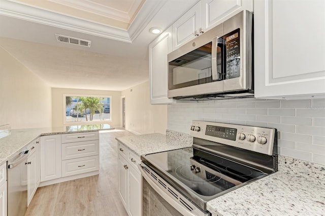 kitchen featuring white cabinets, appliances with stainless steel finishes, and ornamental molding