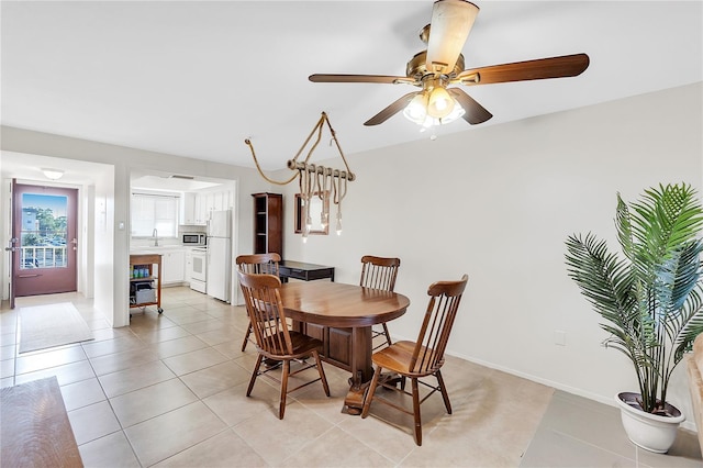 tiled dining room with ceiling fan and sink