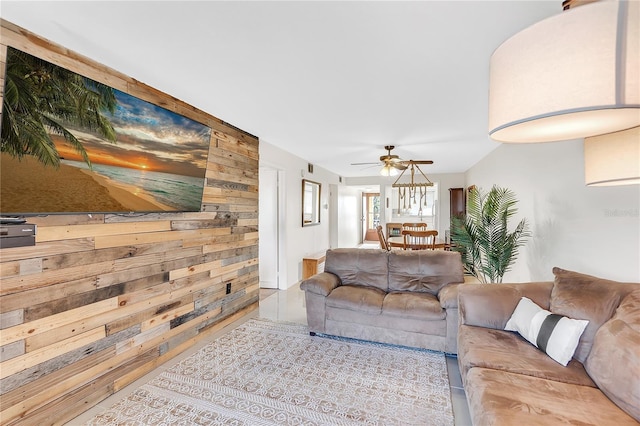 living room with ceiling fan, wooden walls, and light tile patterned floors