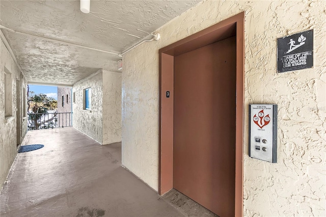 corridor with elevator and concrete flooring