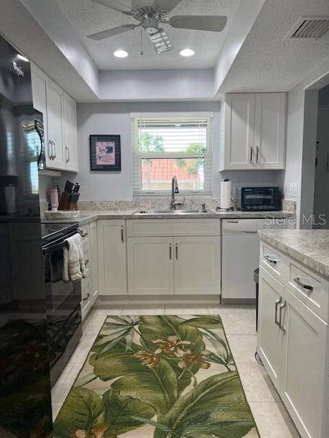 kitchen featuring ceiling fan, sink, light tile patterned floors, white dishwasher, and white cabinets