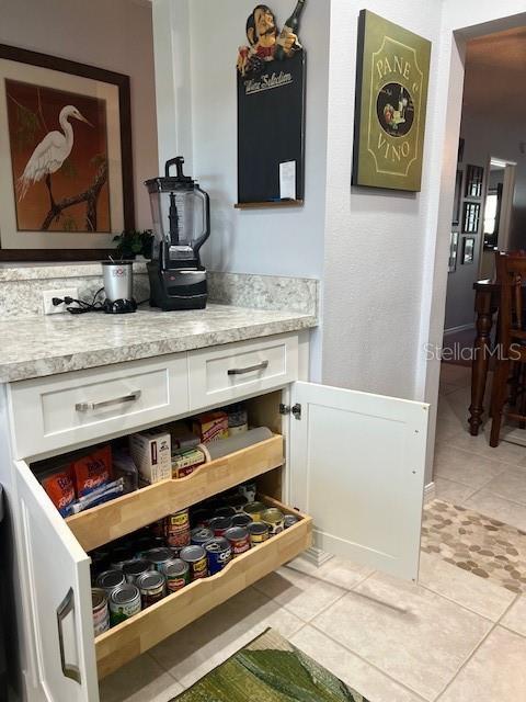 bar featuring light stone countertops, white cabinetry, and light tile patterned floors