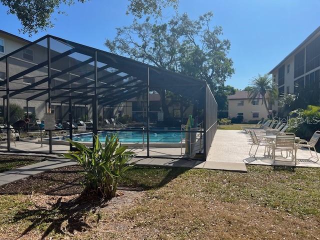 view of swimming pool featuring glass enclosure and a patio