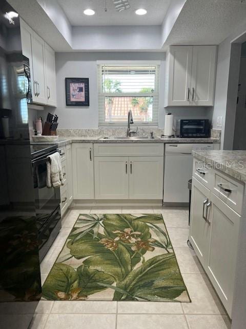 kitchen featuring light tile patterned flooring, black stove, white cabinetry, and sink