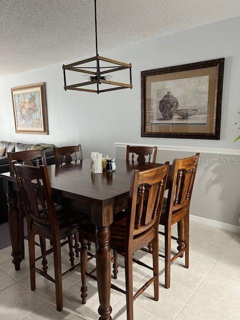 dining room featuring light tile patterned floors, a textured ceiling, and an inviting chandelier