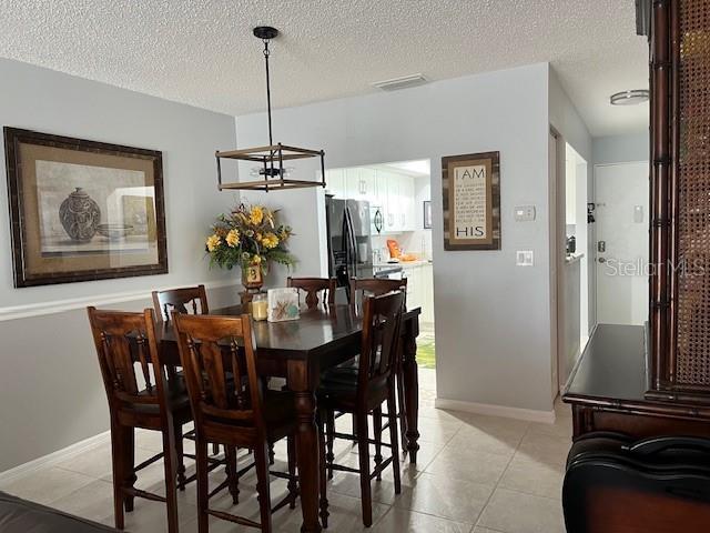 dining space with a notable chandelier, light tile patterned flooring, and a textured ceiling